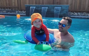 Father and son swimming in a fiberglass pool